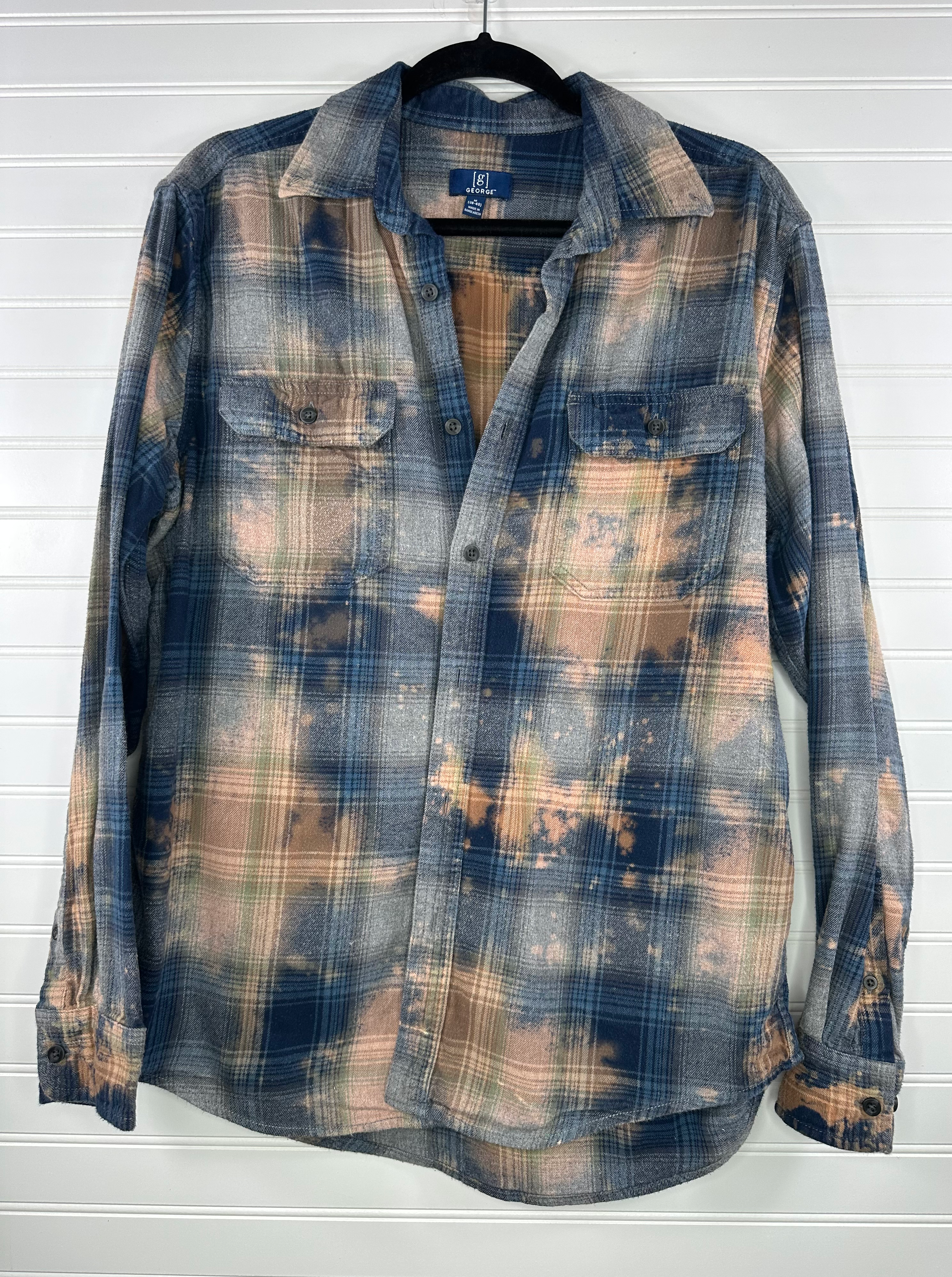 Plaid flannel in blue and gray with bleach splatters in orangey peach color 