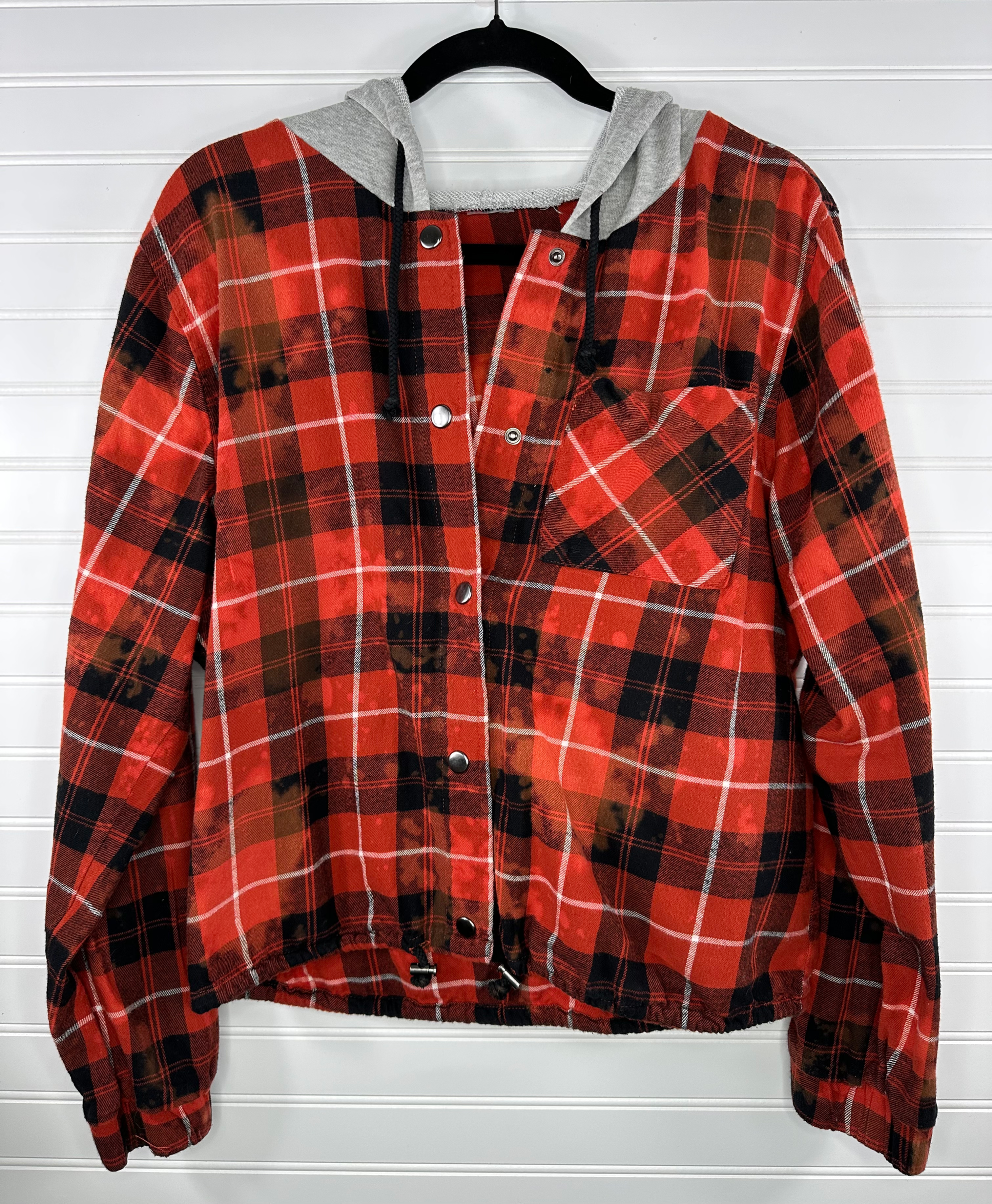 Cropped flannel with hood and snap buttons in orange and black with bleach splatter