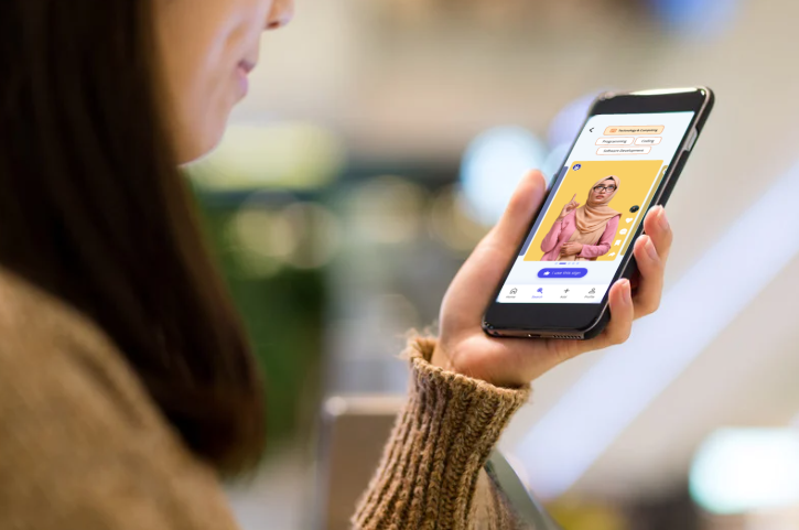 A girl happily holding her phone and looking at the screen while using the sign language app.