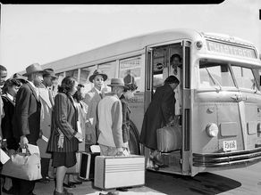 People in suits and hats board a chartered bus with luggage. The mood is orderly and formal, set in a black and white urban environment.