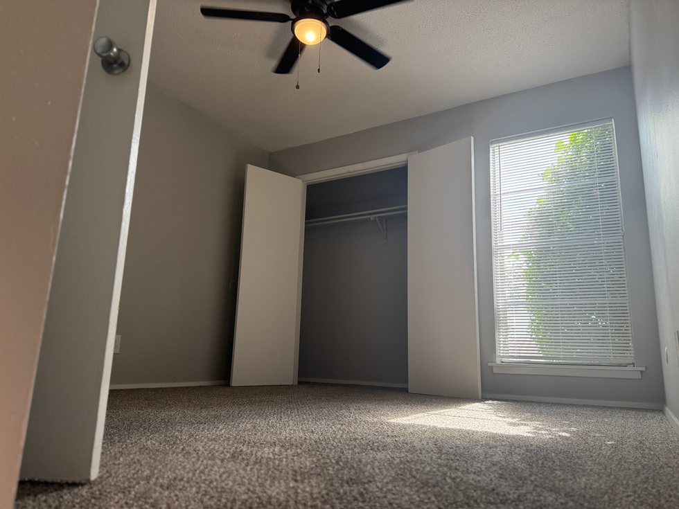 an empty bedroom with a ceiling fan and a window
