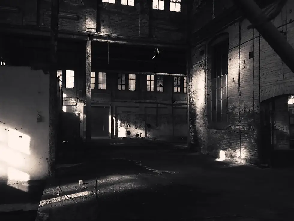 Eye-level view of an abandoned industrial warehouse with broken windows
