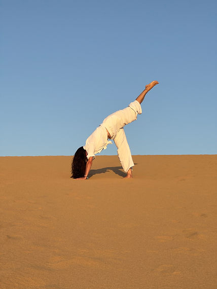 Sandra Bachmann in einer Yoga-Stellung auf einer Sanddühne
