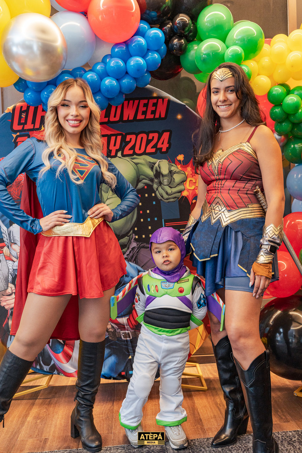 two women dressed as superman and wonder woman pose with a child dressed as buzz lightyear
