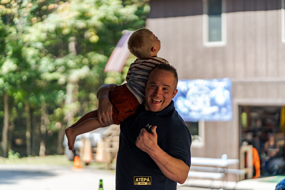 a man holding a little boy on his shoulders with a shirt that says atepa