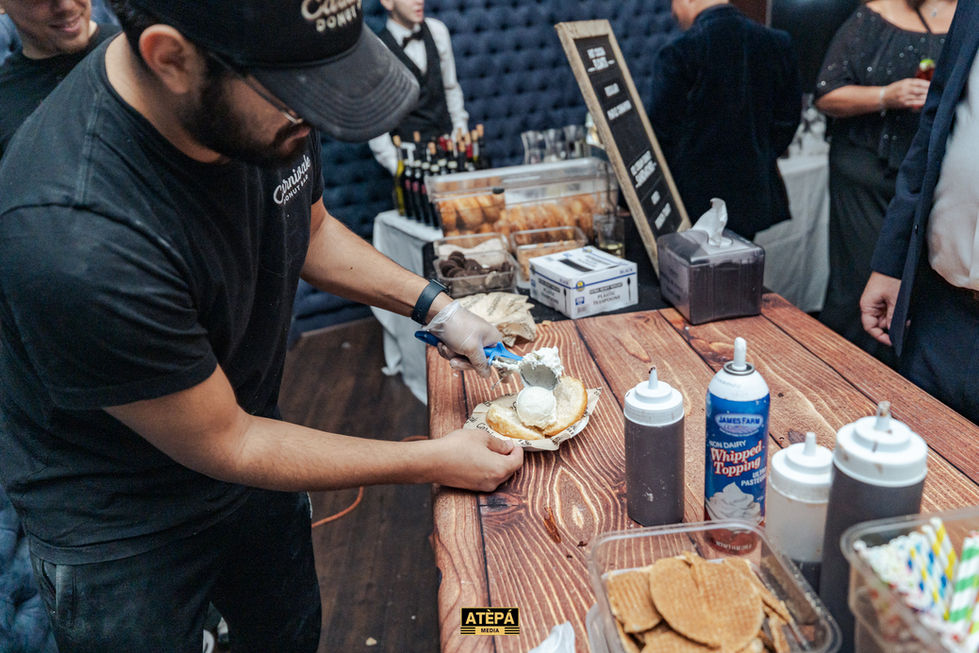 a man wearing a black shirt that says classic donuts is preparing food
