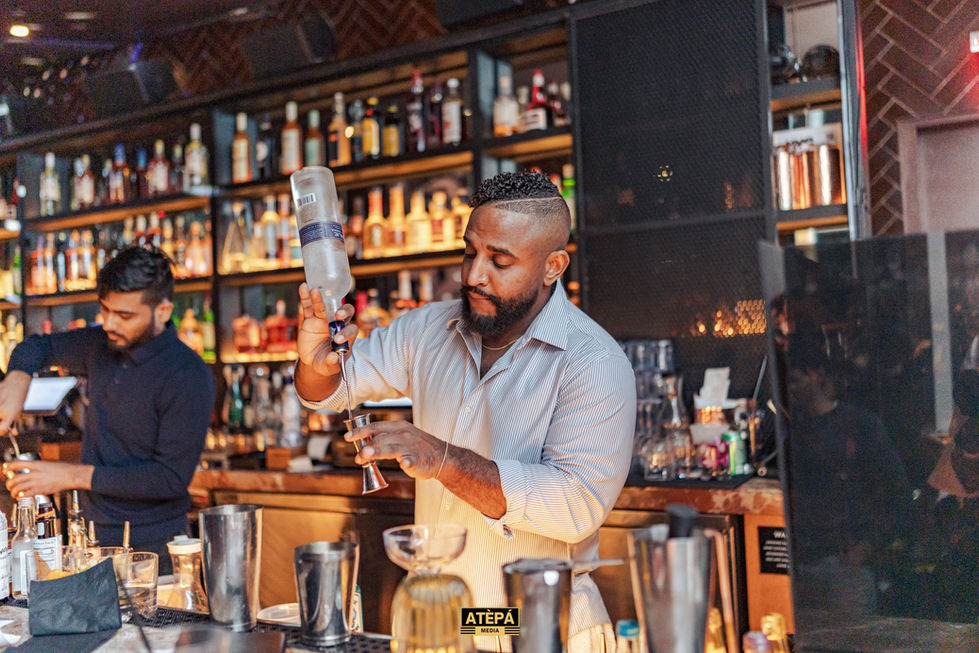 a bartender prepares a drink in front of a sign that says atepa