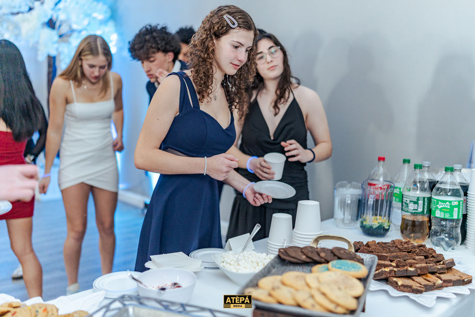 a woman in a blue dress is standing at a table with a tray of cookies
