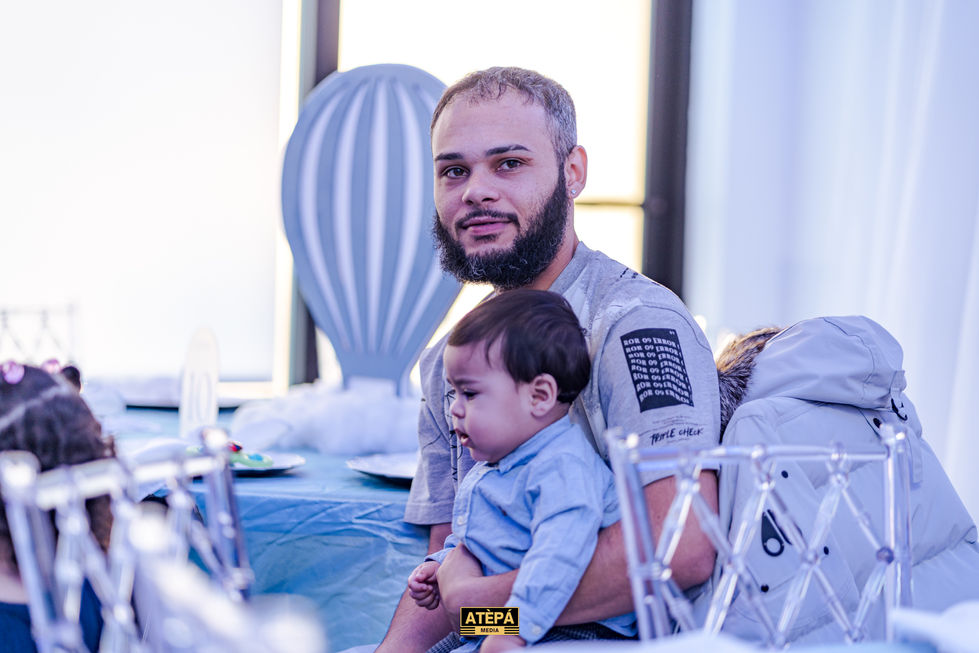 a man with a beard holds a baby in his arms while wearing an atepa shirt