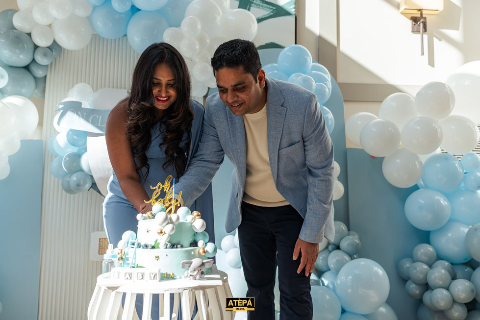 a man and woman are cutting a cake that says baby on it