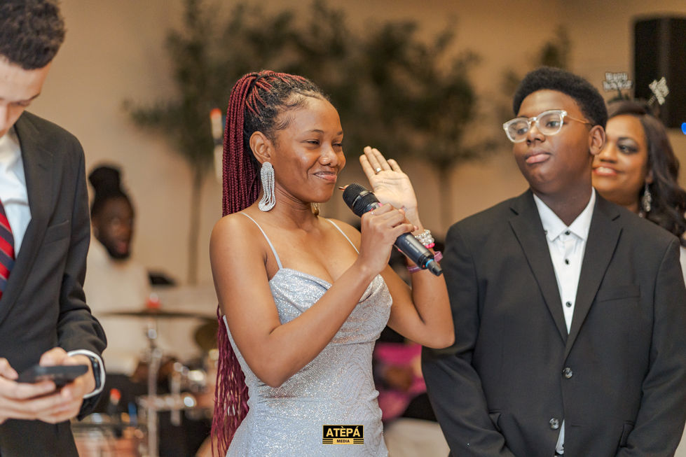 a woman in a silver dress is holding a microphone in front of a man in a suit and a sign that says atepa