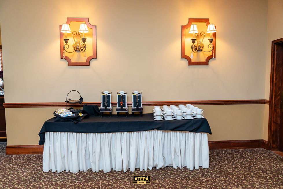 Table with coffee dispensers and cups in a room.