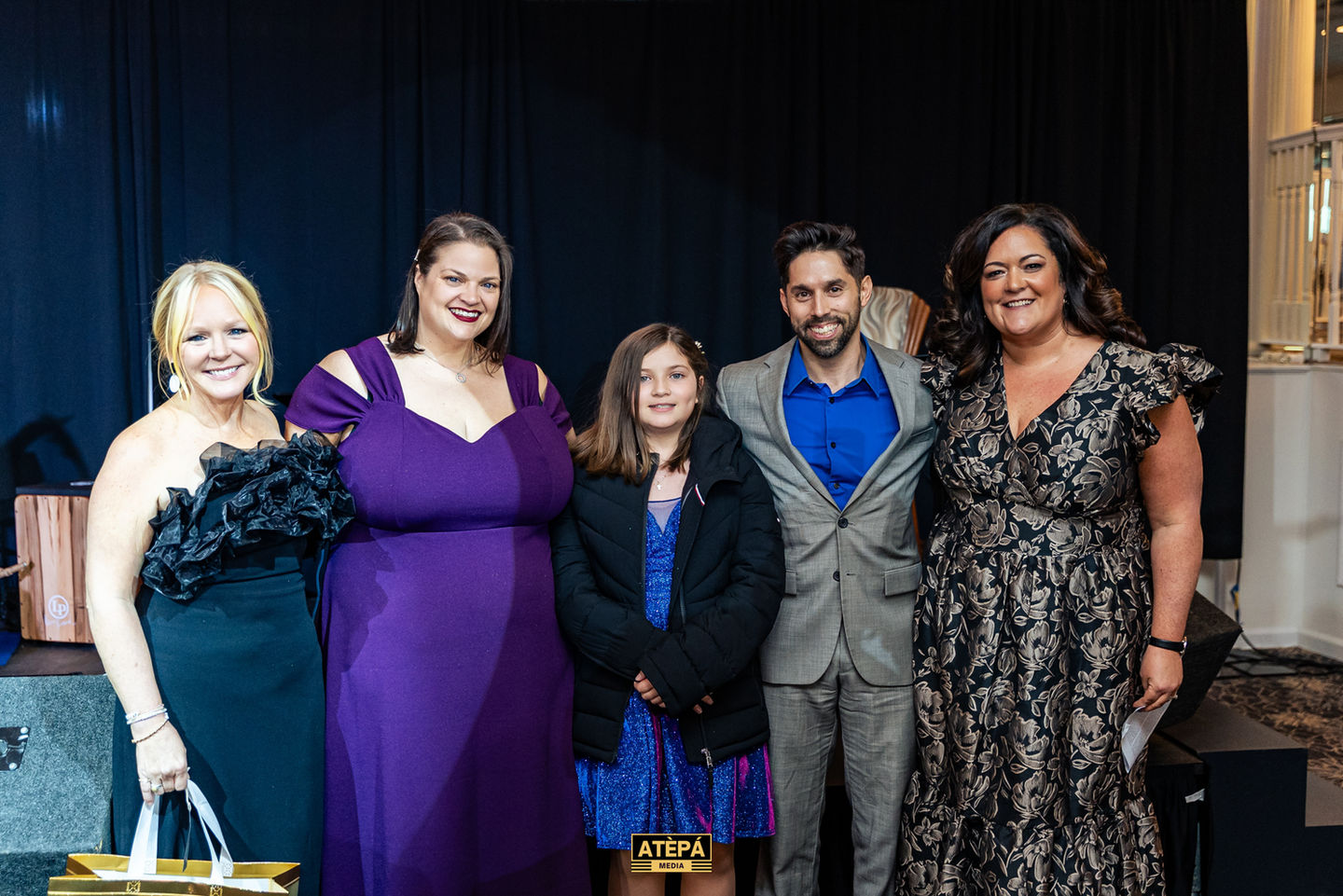 Five people posing together, dressed formally.