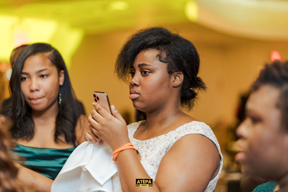 a woman in a white dress is looking at her phone with a photo taken by atepa