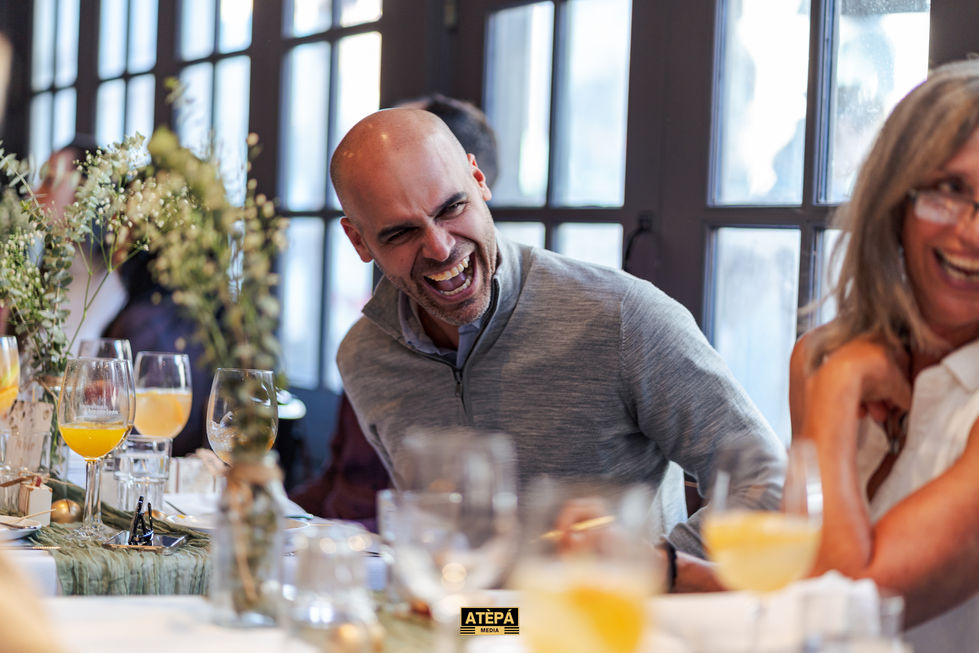 a man laughs while sitting at a table with a sign that says ' atepa ' on it