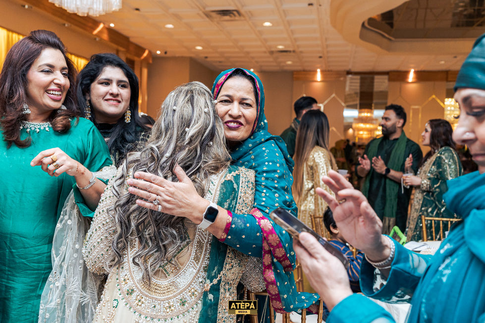 a woman in a green and gold dress is hugging another woman
