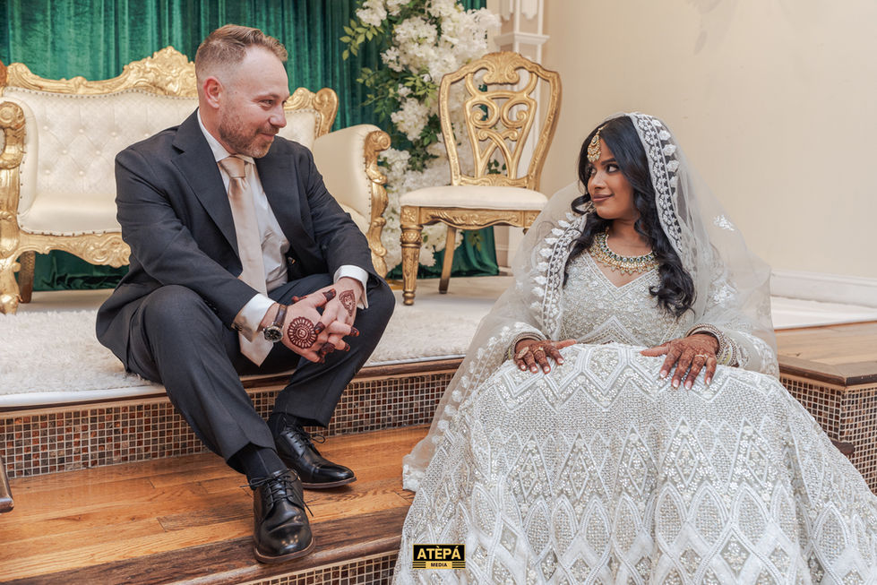 a man in a suit sits next to a woman in a white dress with the word atepa on the bottom