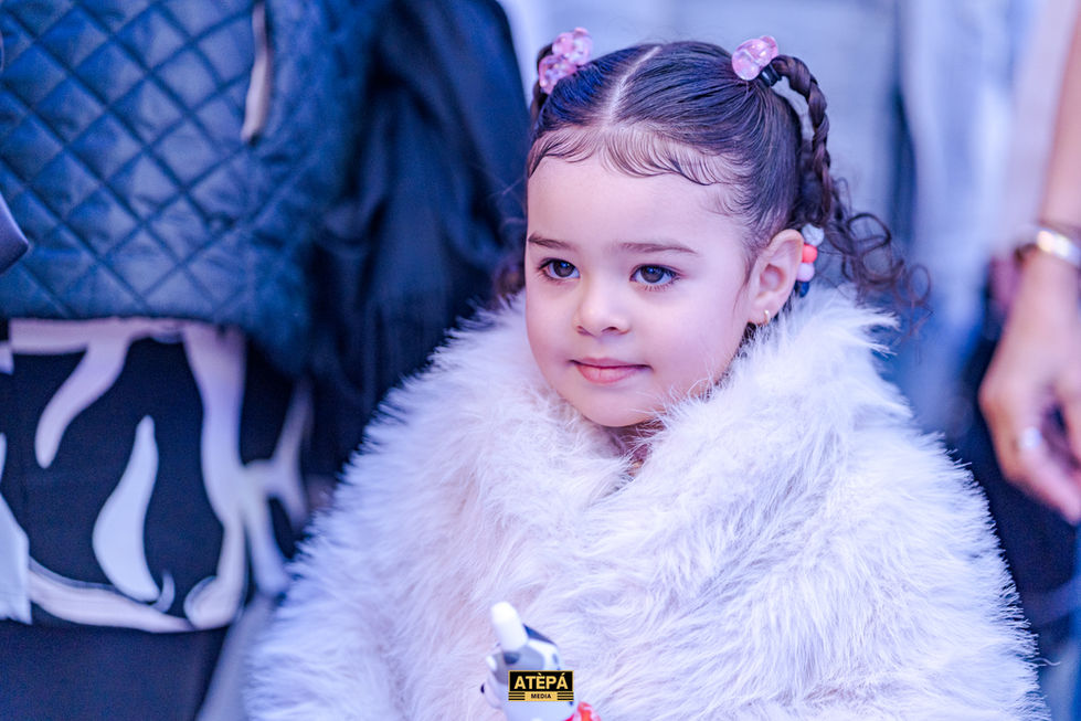 a little girl wearing a white fur coat with the word atepa on the bottom