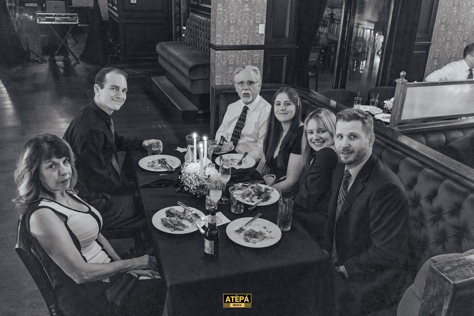 a black and white photo of a group of people sitting at a table with plates of food