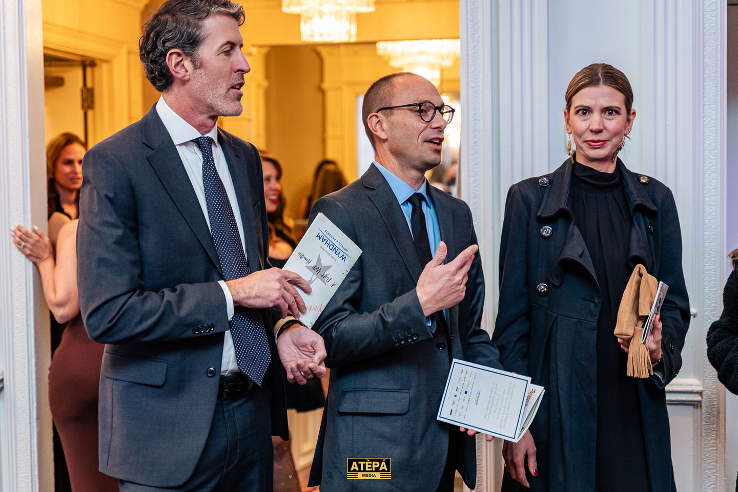 Three people in formal attire having a conversation.