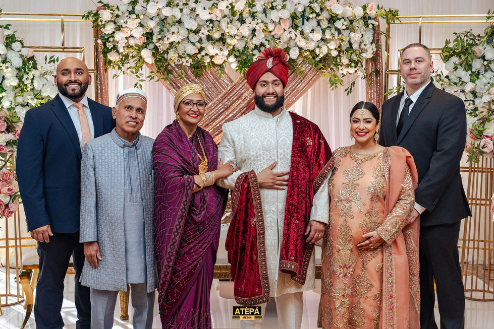 Group photo at a formal event with floral backdrop.
