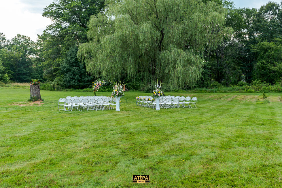 Outdoor wedding setup with chairs and floral arrangements.