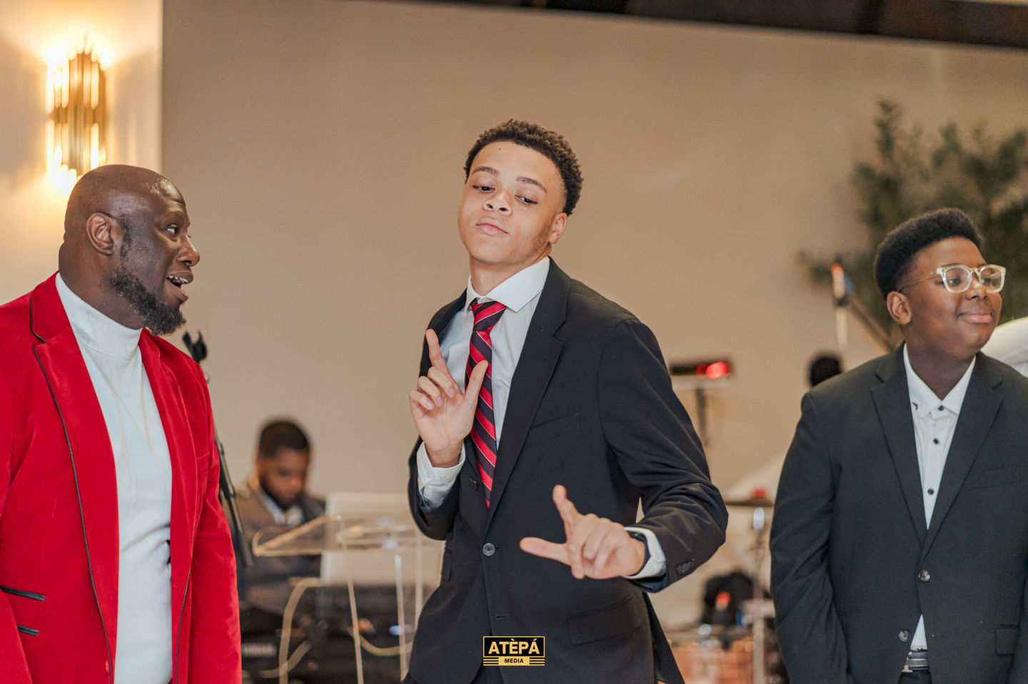 a young man in a suit and tie stands in front of a sign that says atepa
