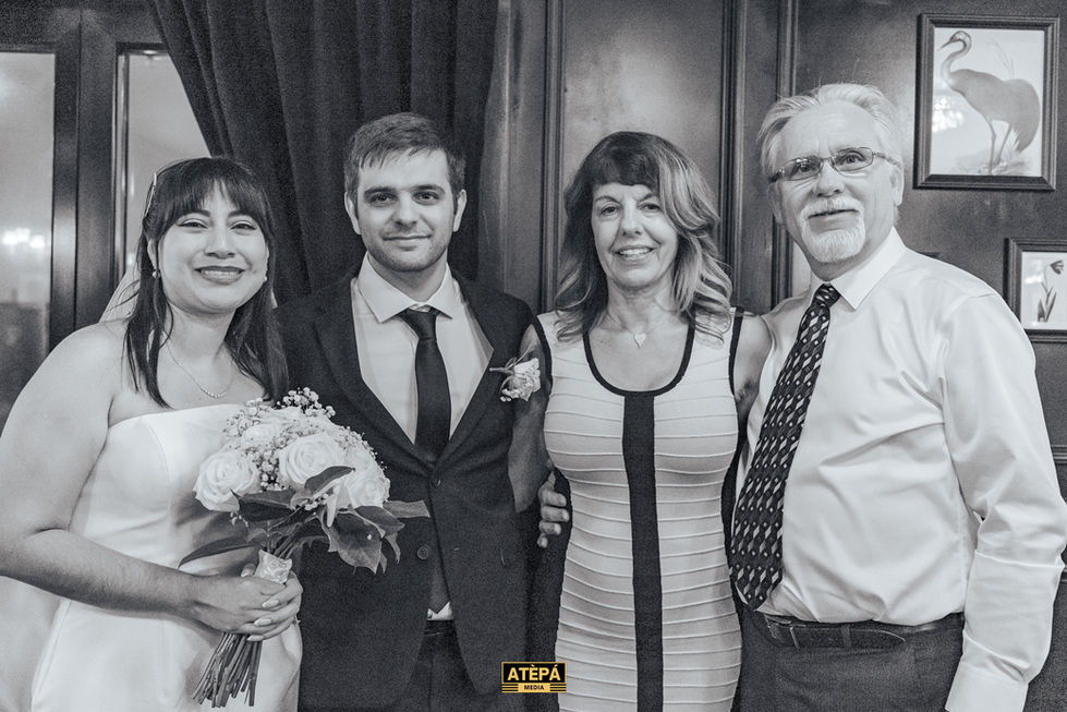 a black and white photo of a bride and groom posing with their parents