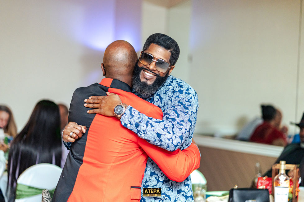 two men hugging with one wearing a shirt that says atepa