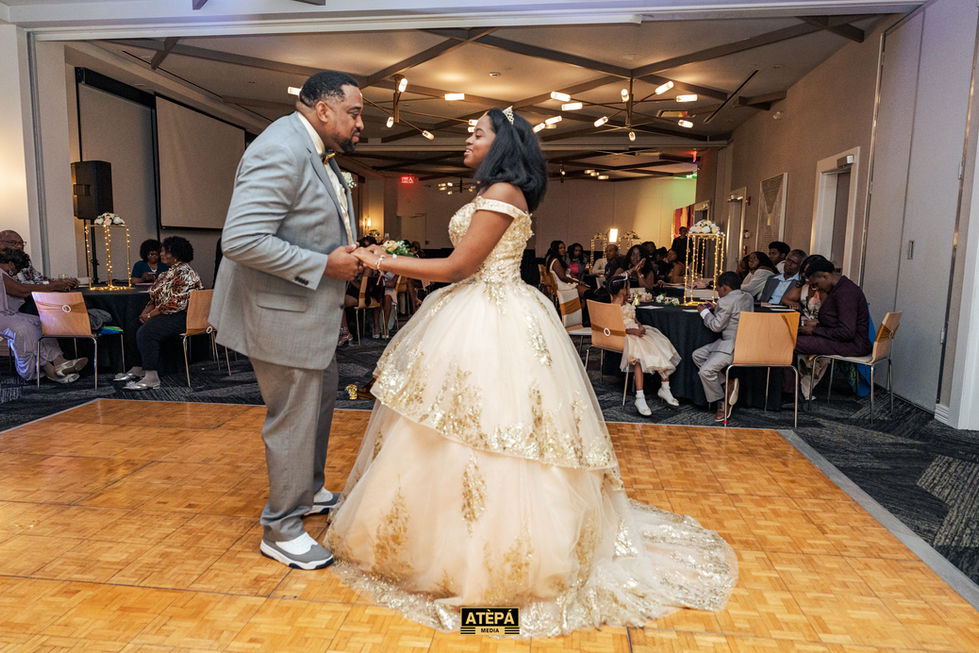 a man in a suit and a woman in a ball gown are dancing in a room with a sign that says atepa