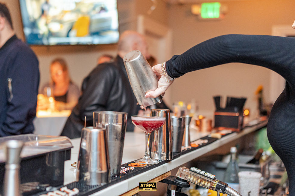 a bartender pours a drink from a shaker into a martini glass