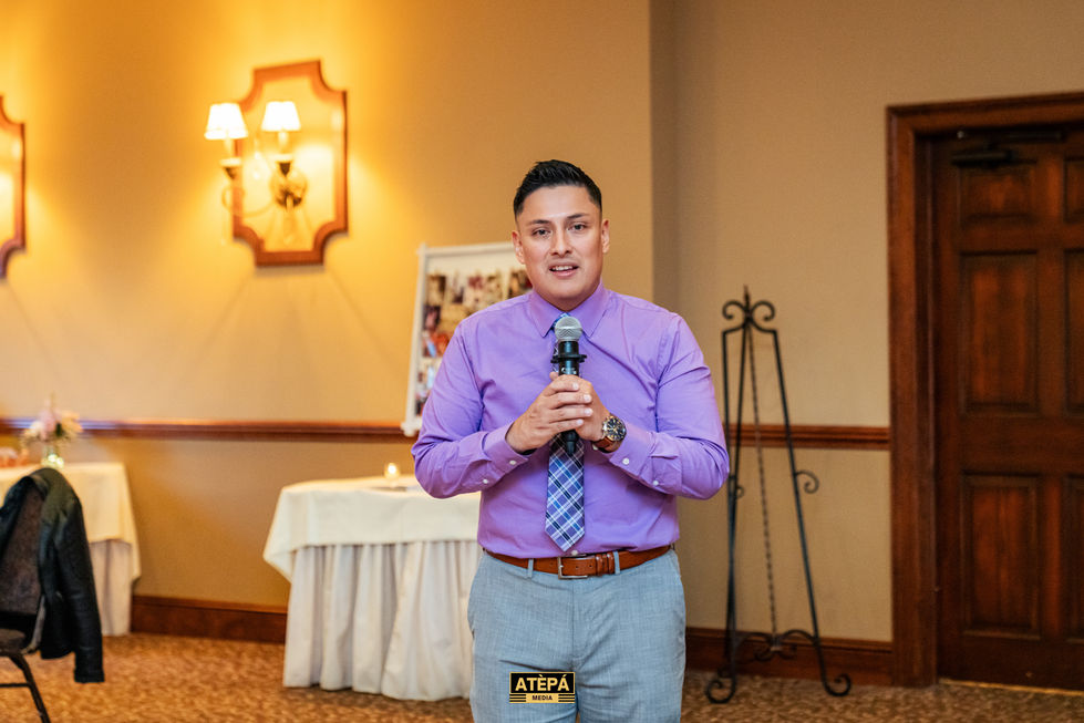 Man in purple shirt speaking into a microphone.