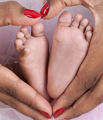 baby feet held in mothers heart shaped hands