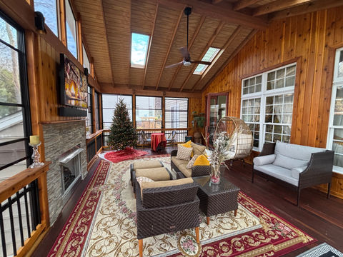 Cozy screened porch featuring a stone fireplace, cedar plank ceiling with skylights, and outdoor entertainment area by Northern Deckworks in Northern Virginia.
