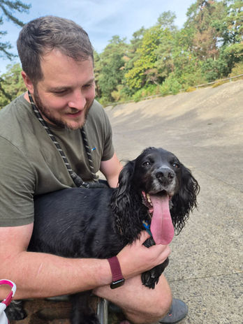 Sam from Wagstaff Walks spending time with a happy black dog outdoors.
