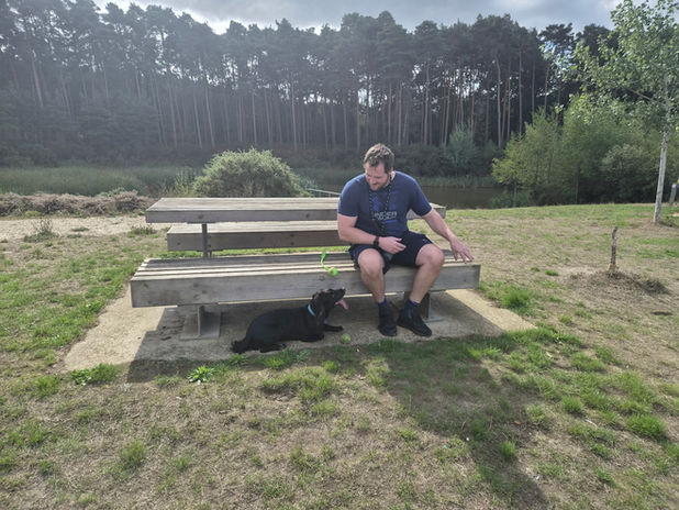 Sam from Wagstaff Walks sitting outdoors with a dog during a walk.