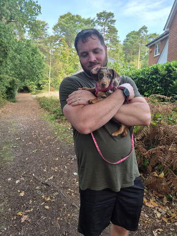 Sam from Wagstaff Walks holding a small dog outdoors near Crowthorne.