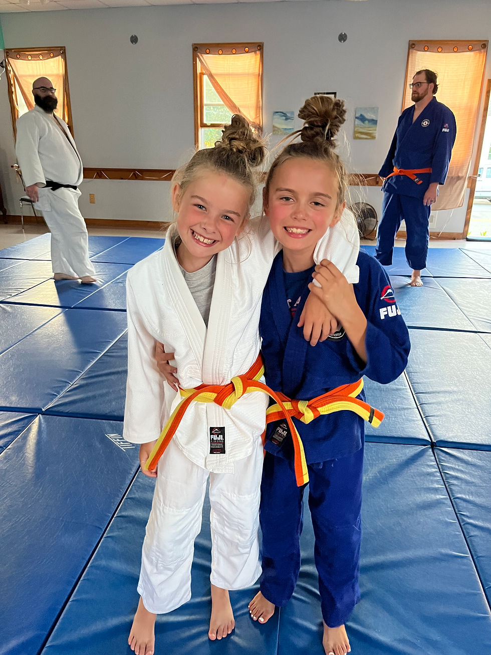 Two girls at kids judo in Buzzards Bay MA smiling on mats.