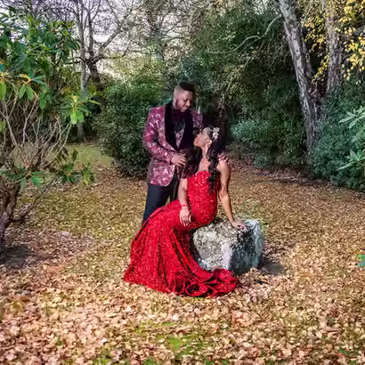 A groom in a patterned suit and a bride in a sparkling red dress posing among autumn leaves at Omarino Estate, crafted by expert Christchurch wedding photographer Kiwi Moments Media.