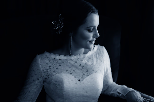 Christchurch wedding photography at The Vines Club – serene bride seated in soft light, showcasing elegant hair styling in a romantic setting. Black and white. Captured By Kiwi Moments Media.
