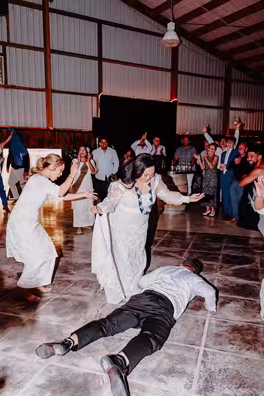 Bangor Farm wedding reception with guests dancing and celebrating, featuring the bride dancing with people in a barn-like venue. Christchurch wedding photographer Kiwi Moments Media.