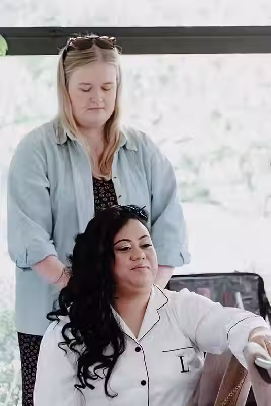 Bangor Farm wedding: bride in a white robe getting her hair styled by a makeup artist, bridal preparation in Christchurch.
