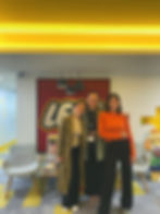 Three participants smiling in front of a LEGO logo wall during a team experience workshop hosted at LEGO offices.