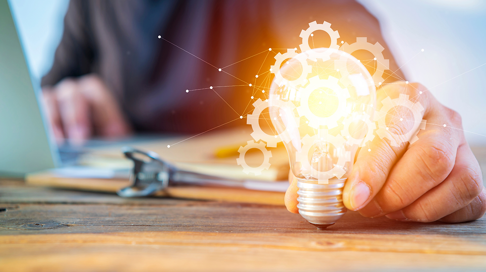 Hand holding a glowing lightbulb icon over tools symbolizing creativity and innovation driving spark