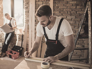 Professional carpenter carefully installing decorative wood trim along a wall baseboard.