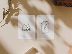 Two minimalist cards on a beige surface, one with "moonlight interior design" and the other with "GOLDEN MAGIC JEWELRY." Shadows and leaves decorate.