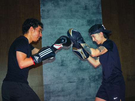 Boxer training with coach by doing padwork