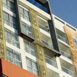 Edificio Aqua Tran, con estructura moderna y ventanas en un día soleado.  Louvers, Puertas correderas, ventanas y muro cortina hechos por ALUGAV. Torre Downtown Santo Domingo