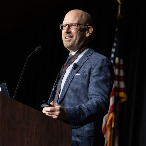 White male presenting at conference and US flag