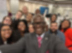 Eddie Moore Jr. smiling while taking a selfie with a multi racial group of conference goers
